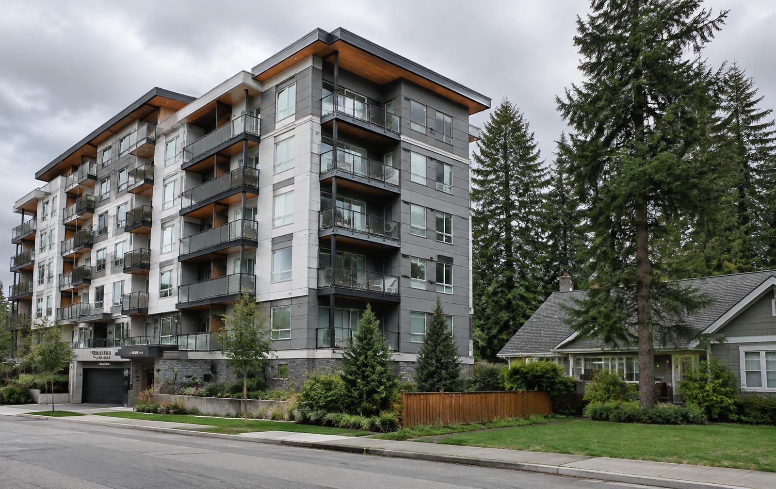 Modern condo building beside a single-family home on a tree-lined Bellevue street